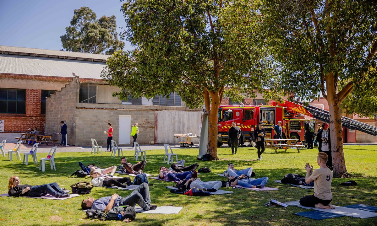 People outside doing yoga with fire truck in distance